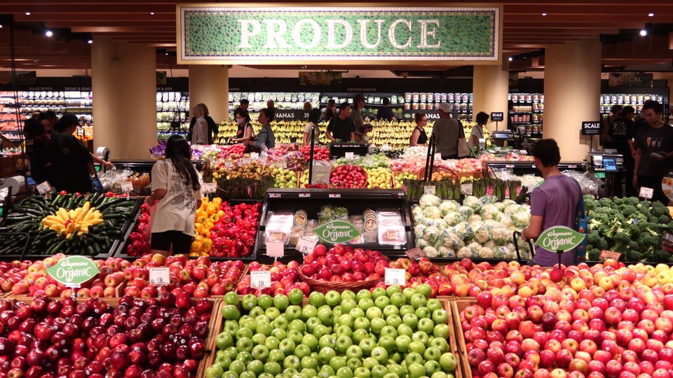 People walk through the produce department at a grocery store