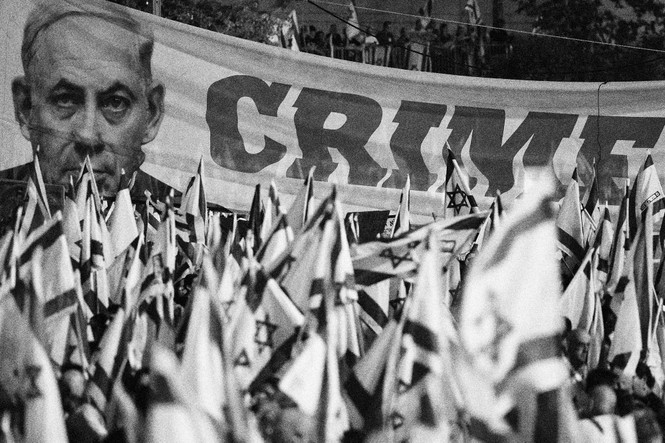 Picture of protesters waving national flags and a banner bearing a picture of Prime minister Benjamn Netanyahu as they march against the Israeli government's judicial overhaul plan in Tel Aviv on July 29, 2023. 