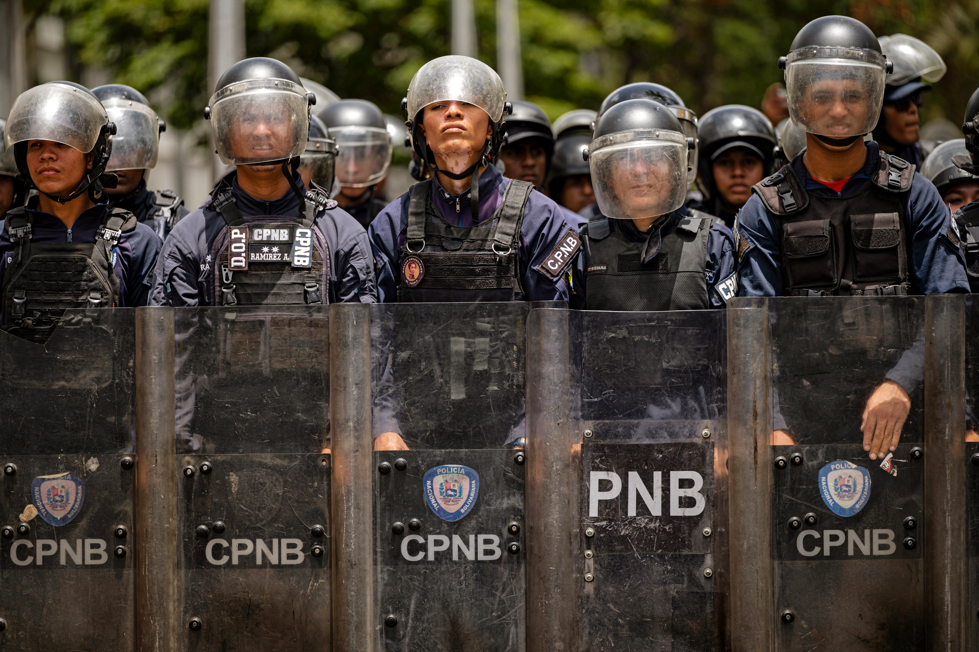 a line of Venezuelan security forces dressed in body armor and holding riot shields