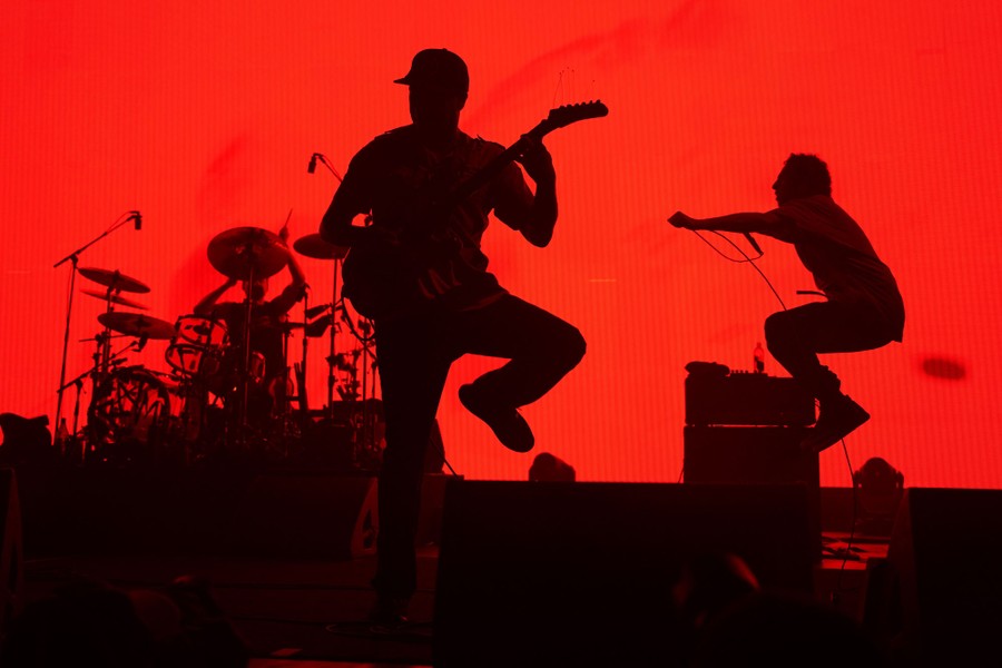 Musicians perform on stage in front of a red screen.