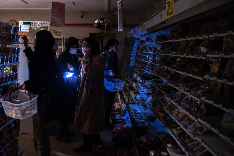 Several people are shop in a dark store.