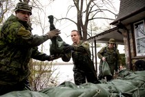 Canadian soldiers place sandbags outside a home in a flooded residential neighbourhood.