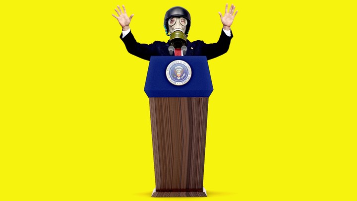 President Trump stands at a podium while wearing a gas mask with his hands raised.