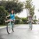 A mother and teen daughter ride bikes.