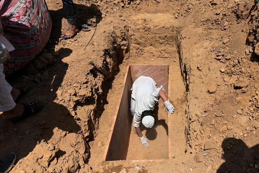 A person checks the interior of a newly-dug grave.