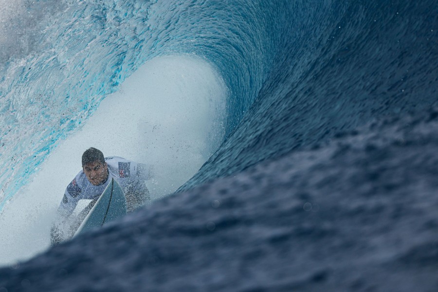 A surfer inside the curl of a large wave