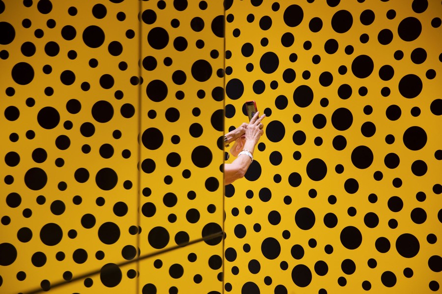 Arms are seen in the midst of a room covered in yellow with black polka dots.