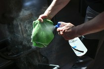 A person sprays a cloth with cleaning solution.