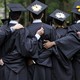 College graduates are shown from behind, with arms around each other 