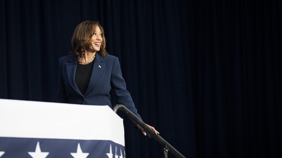 Kamala Harris smiles and walks up steps at a campaign event.