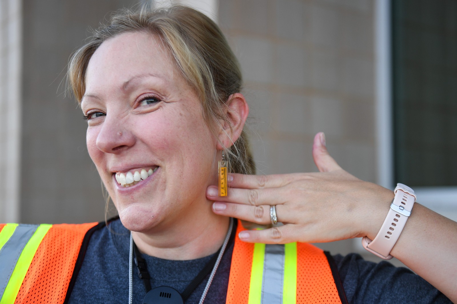 A teacher smiles while posing, showing off her ruler-shaped earrings.