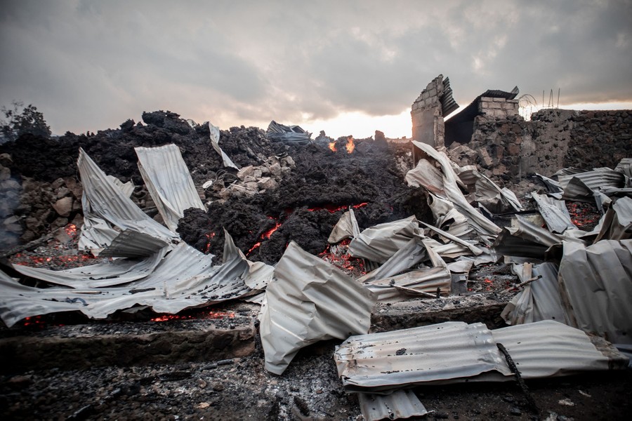 Damaged buildings sit among rocky lava.