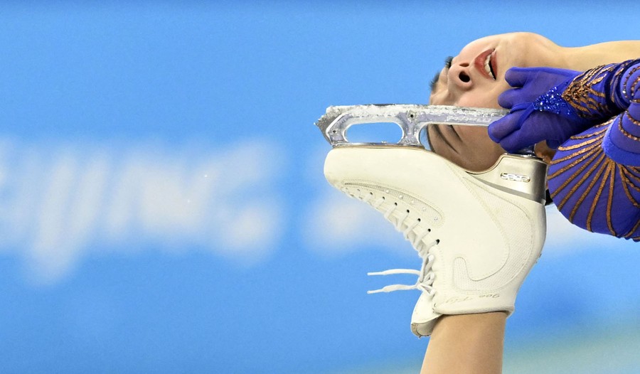 A figure skater is seen during a performance, her skate pulled up close to her face.