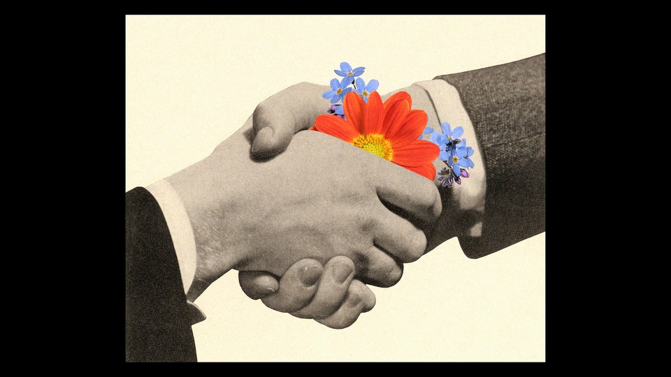 A black-and-white image of two people in suits shaking hands. There are flowers in between their palms.