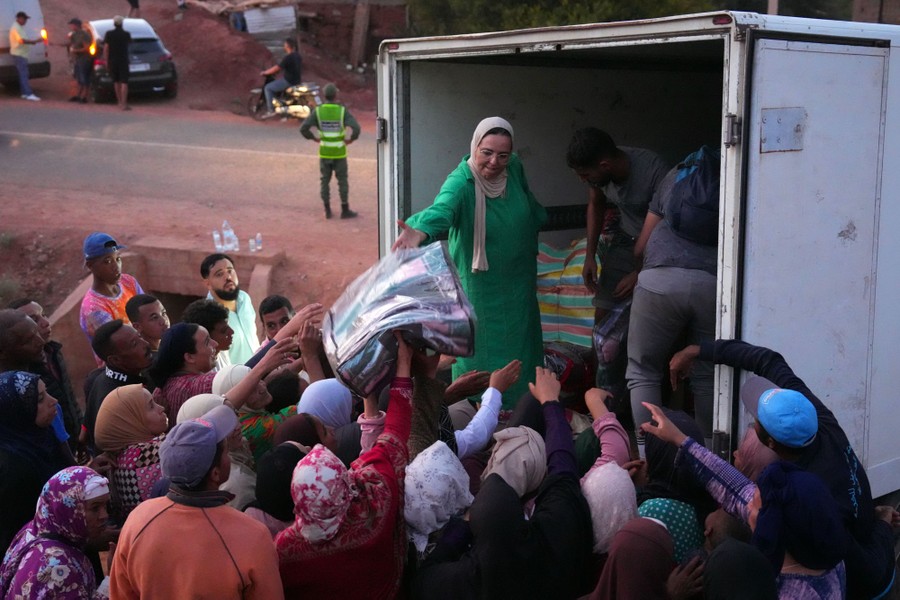 People hand blankets to a small crowd, from the back of an open truck.
