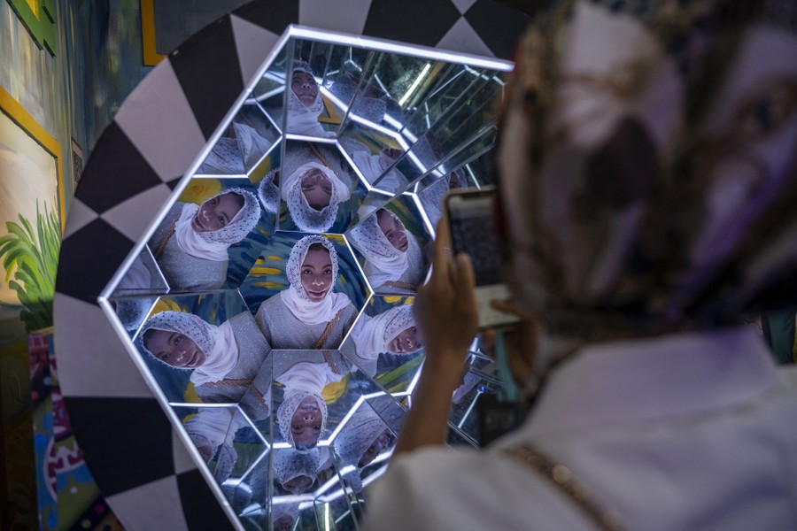 A woman is photographed in an angular mirrored exhibit.