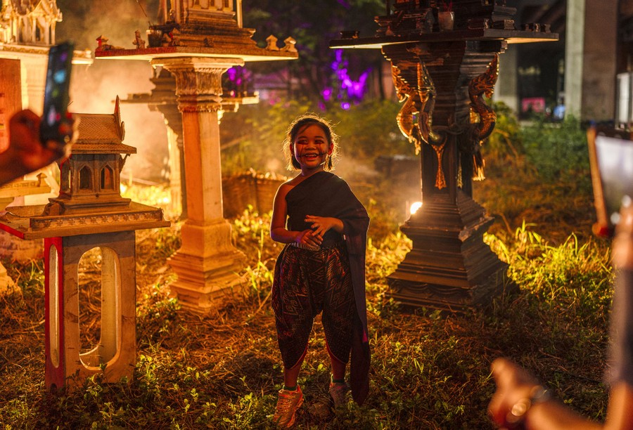 A girl in Halloween makeup and costume poses amid spooky decorations.