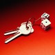 two keys attached to a keychain with two dice on it, against an ominous red background