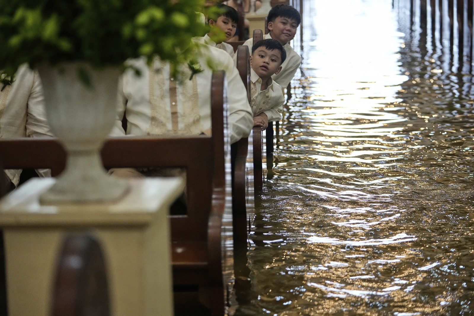 Wedding guests lean out over a flooded church aisle to watch the ceremony.