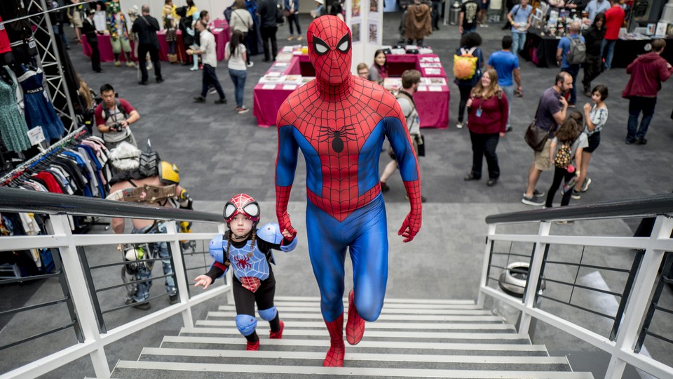 A man dressed as Spider-Man walks up stairs with his daughter.