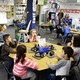 Kids sit at a table in a classroom. 