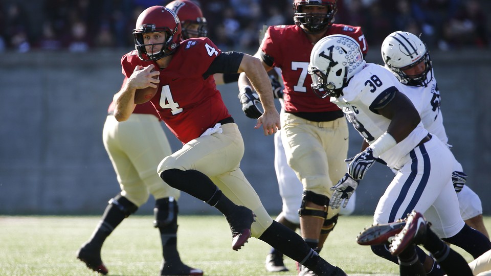A Harvard player runs with the football away from the Yale defense