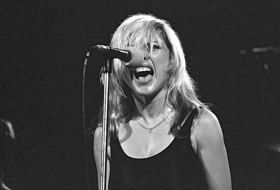 Debbie Harry sings into a microphone.