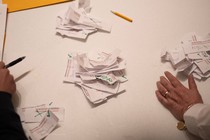 Hands on a desk with ballot slips during the 2024 Iowa Republican caucuses