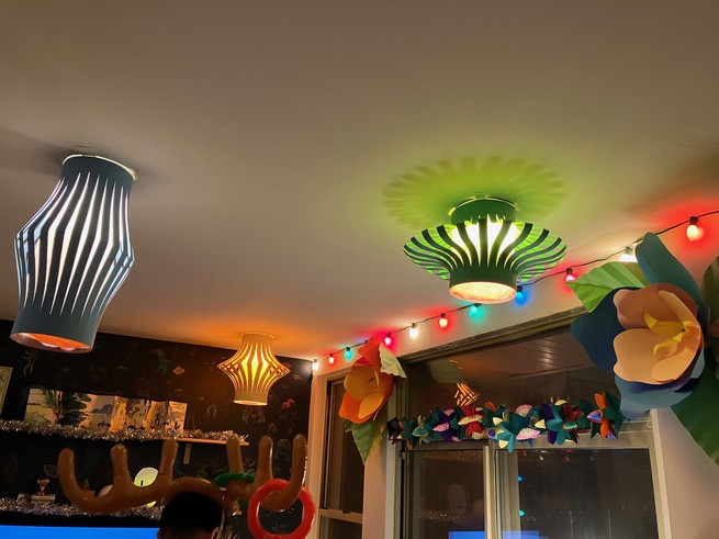 An apartment decorated for a party with Christmas lights, colorful paper lanterns, and huge paper flowers.