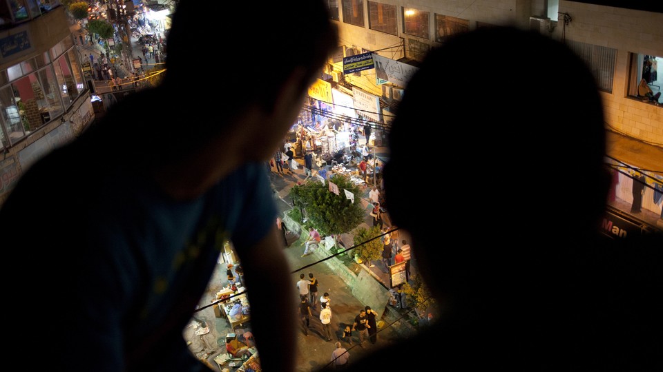 Two people watching a street below.