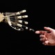 A photograph of a robotic hand reaching out to touch the finger of a human hand.