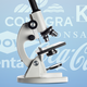 A cut-out image of a microscope in front of a light blue background with logos for companies including Nestle, Dow, and Coca-Cola