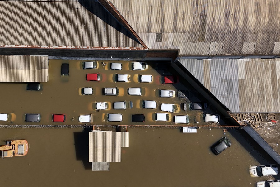 Partially submerged vehicles sit in a flooded parking lot.