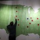 A man reaches up to touch a map of the United States decorated with red and blue stars.