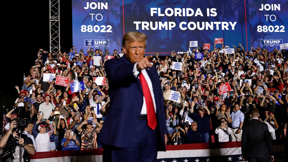 Donald Trump in a red tie and blue suit at a Florida rally
