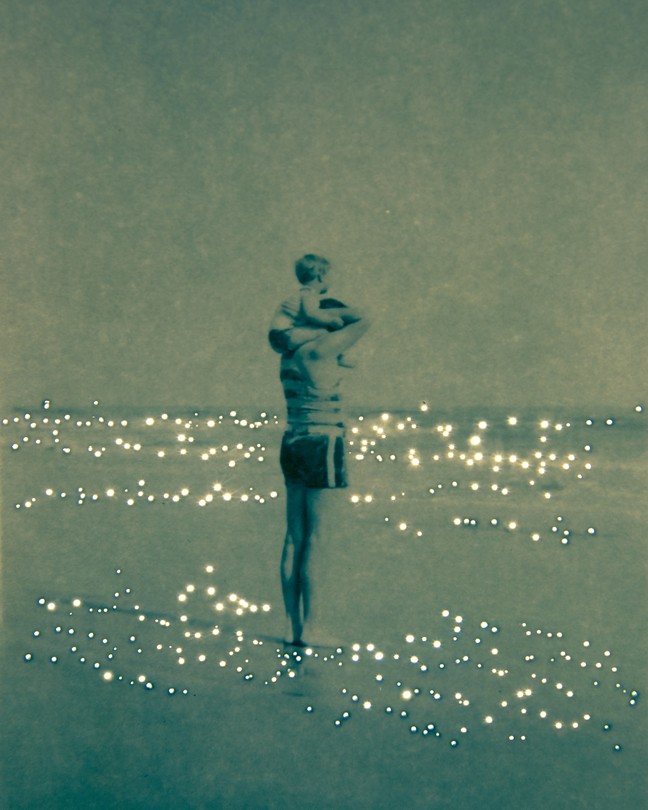 An illustration of a man standing in the ocean with a young boy on his shoulders. The sand is glimmering, catching the light.