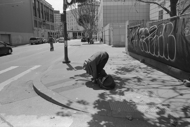 a man pulls down his pants on a sidewalk