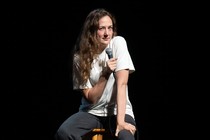 Jacqueline Novak sits on a stool while performing her comedy routine