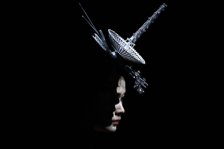 A close view of a model wearing a hat shaped like a stylized radio antenna.