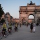 Cyclists stream past the Arc de Triomphe du Carrousel in Paris.