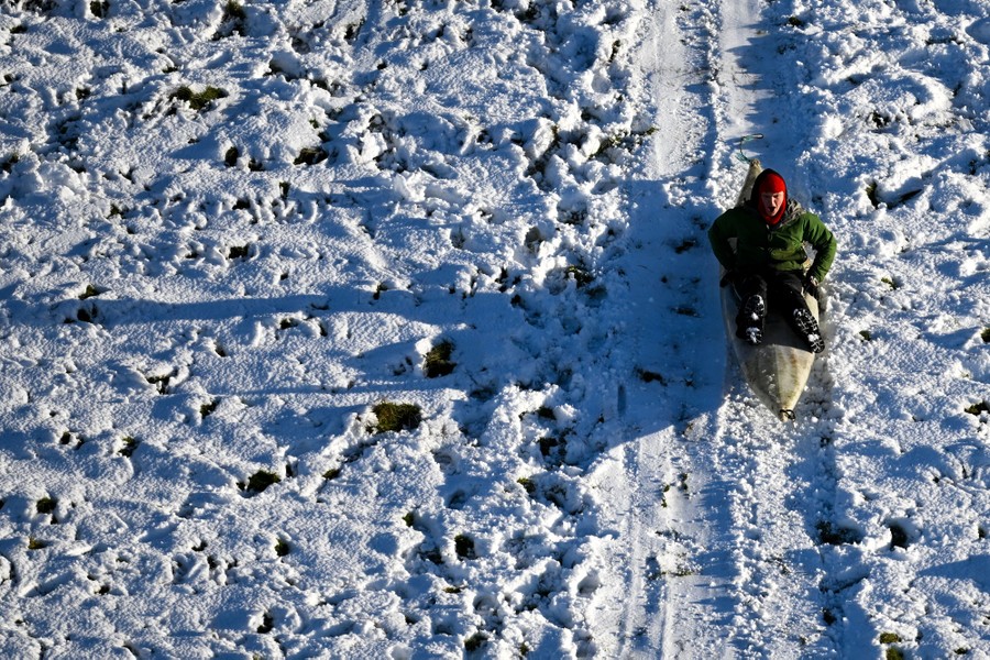 A person sleds down a hill in what appears to be a kayak.